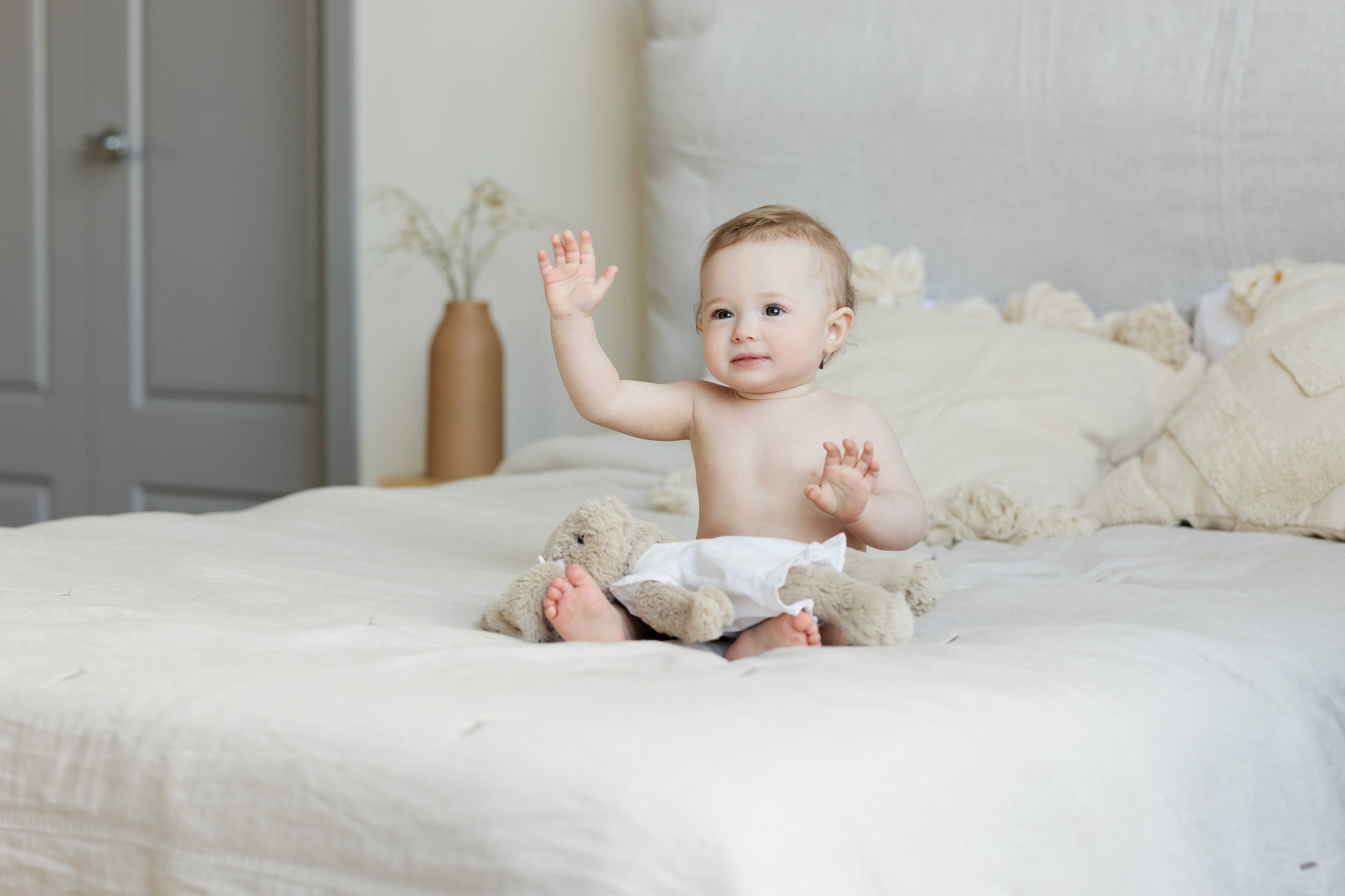 Baby on bed waving