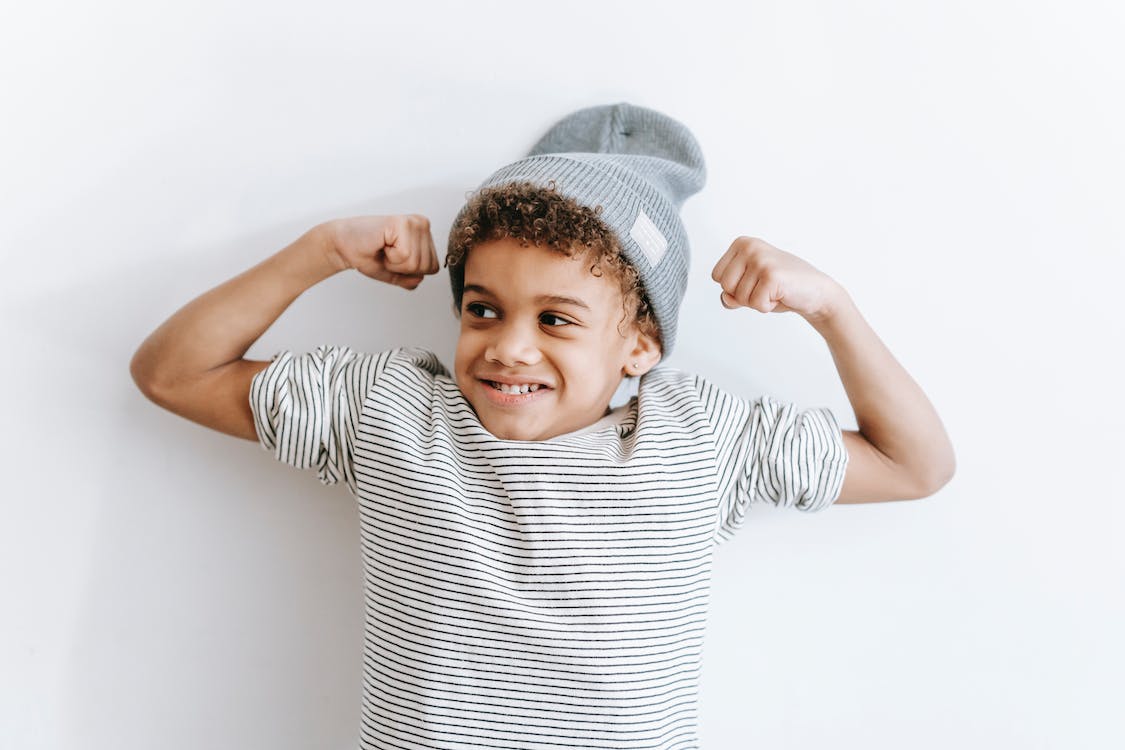 Young boy smiling and showing off muscles
