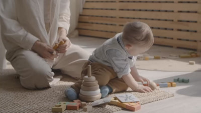 Baby boy playing with wooden toys on floor
